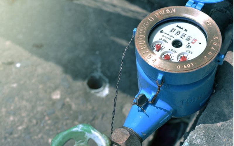 Close up of a blue water meter sitting above a concrete walkway