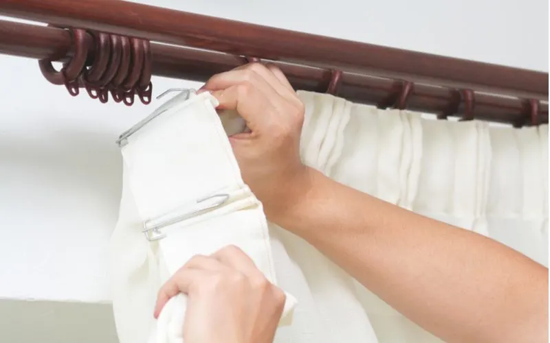 Image of a guy installing curtains for travers rods on a wooden rod