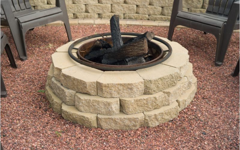 Simple wood burning round retaining wall block firepit idea with a charred metal insert