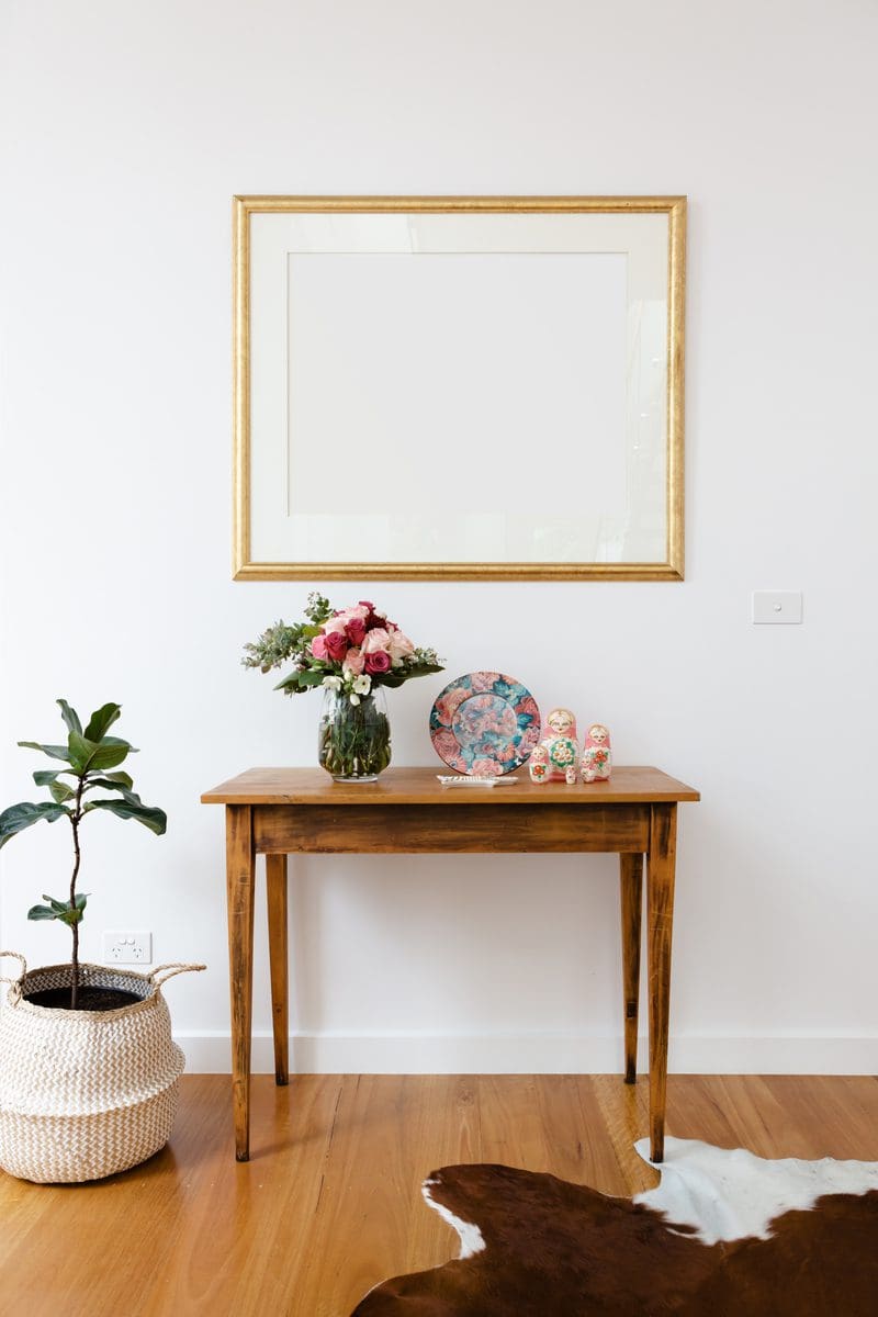 Gold picture frame with white matting mounted on the wall in a white room as an example for rustic-style entry table decor ideas