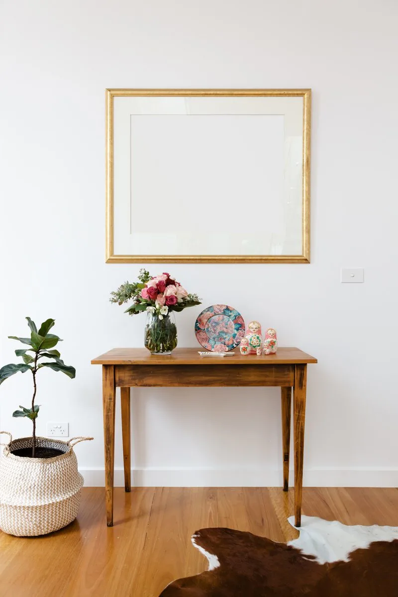 Gold picture frame with white matting mounted on the wall in a white room as an example for rustic-style entry table decor ideas