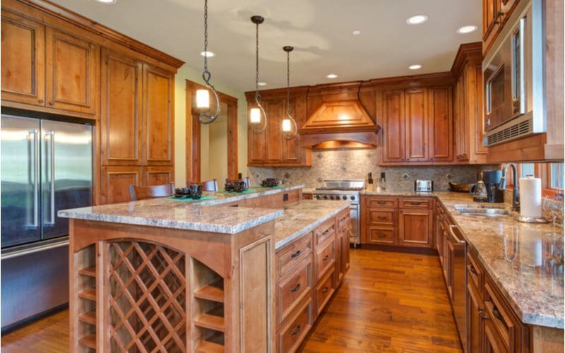 Kitchen with honey maple cabinets and tan granite is well lit and has medium-brown colored hardwood floors