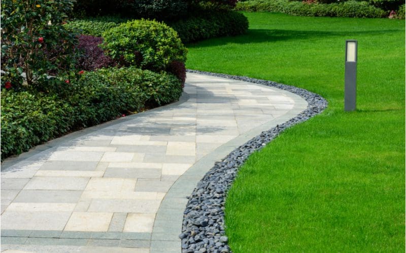 Stone and paver lawn edging idea separating the walkway from the lush green fescue lawn