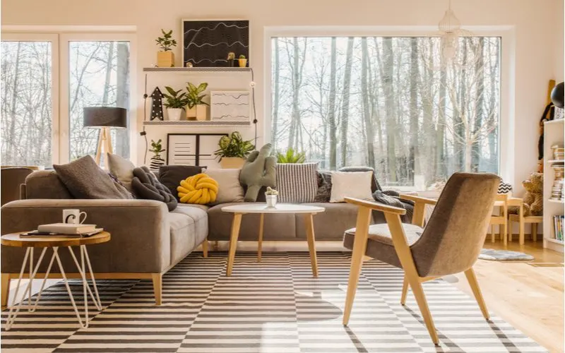 Living room toy storage idea in a Scandinavian living room with a big picture window that overlooks a forest 