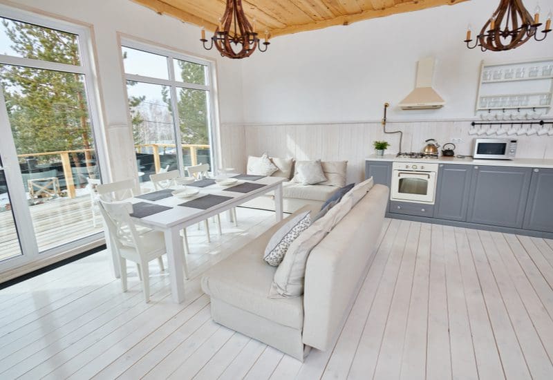 Photo of a cottage interior decorated in a minimalist style with white wooden floors and natural wooden ceilings