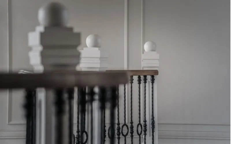 White railing newel caps in the Colonial style with metal spindles for a piece on decorating ideas for stairs