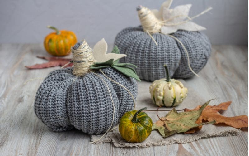 Knitted pumpkins made from grey yarn and brown twine for a piece on fall centerpiece ideas