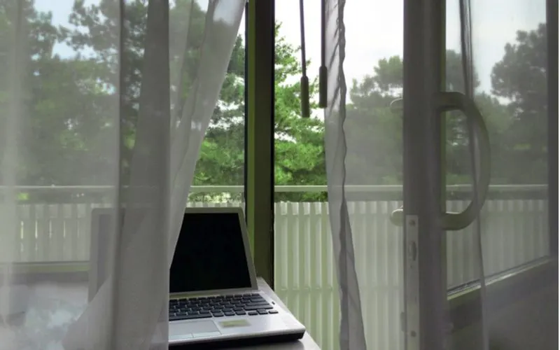 Privacy sheets used as window treatments for sliding glass doors in front of a laptop overlooking a balcony