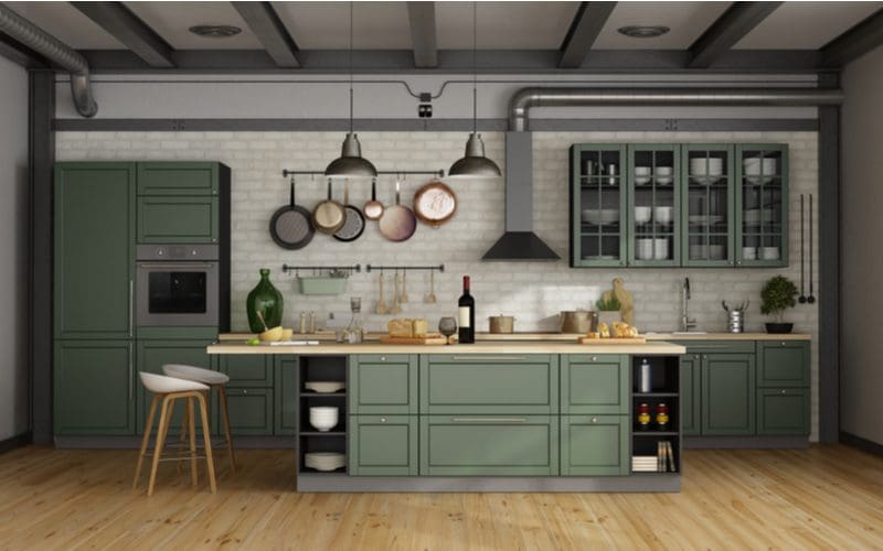 Vintage loft with mint-colored rustic cabinets in the kitchen with natural wood flooring and grey ceilings and white brick subway tile backsplash