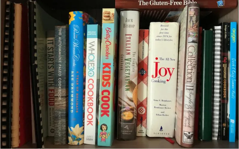 Books lined vertically on a bookshelf in a kitchen