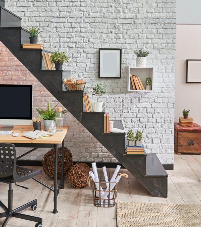 Stair decorating idea featuring small plants in pots sitting next to books on the open staircase