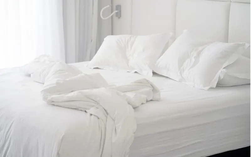 Image for a post on comforters vs. blankets featuring a white comforter on a bed that's all messy and scrunched up