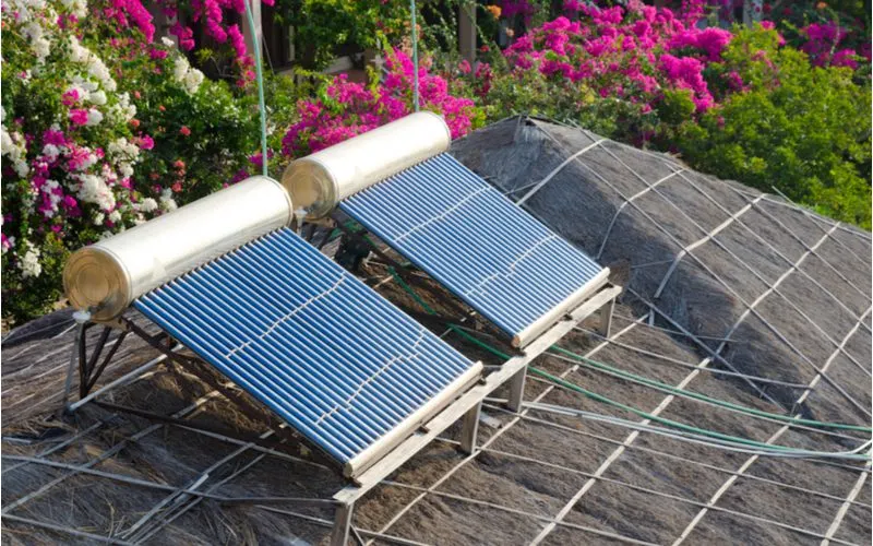 Solar powered water heater outside a home on a thatched roof