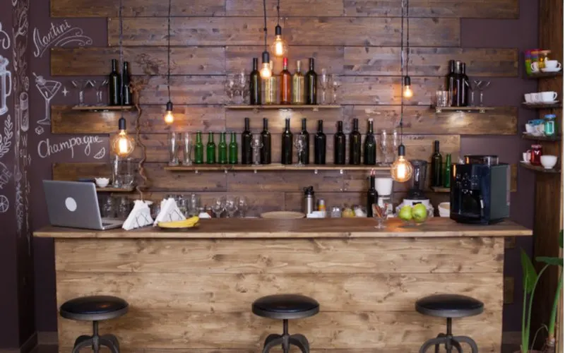 Cocktail bar made of wooden pallets with industrial style light fixtures hanging from the ceiling in an idea for a bachelor pad