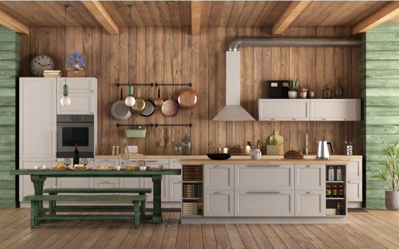 Short and sweet rustic cabinets painted grey-cream coloring next to a vertical grey shiplap wall acting as backsplash