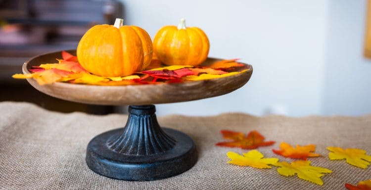 Colorful fall centerpiece with small pumpkins sitting on a black metal platform