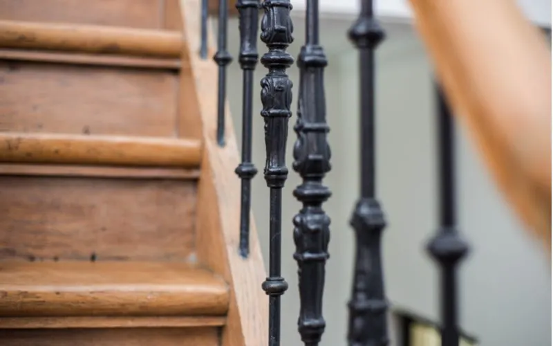 Stair decorating idea featuring a close-up of a railing spindle made of metal next to ornate wooden stairs
