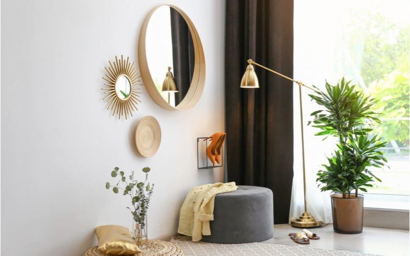 Round boho-style mirrors with metal edging an one with a sun-style pattern above a grey rug in a transitional style home
