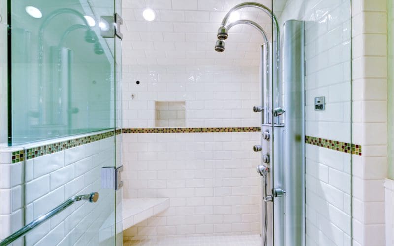 Shower with an average sized bench in the corner for shaving legs with an otherwise drab subway tile surround