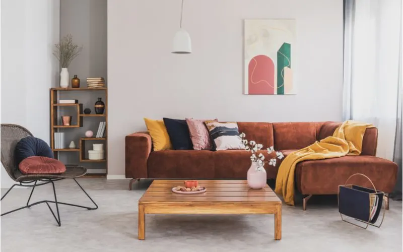 Image titled how to pick throw pillows for brown couches featuring a light beige walled room with a dark brown couch with yellow and blue throw pillows on it