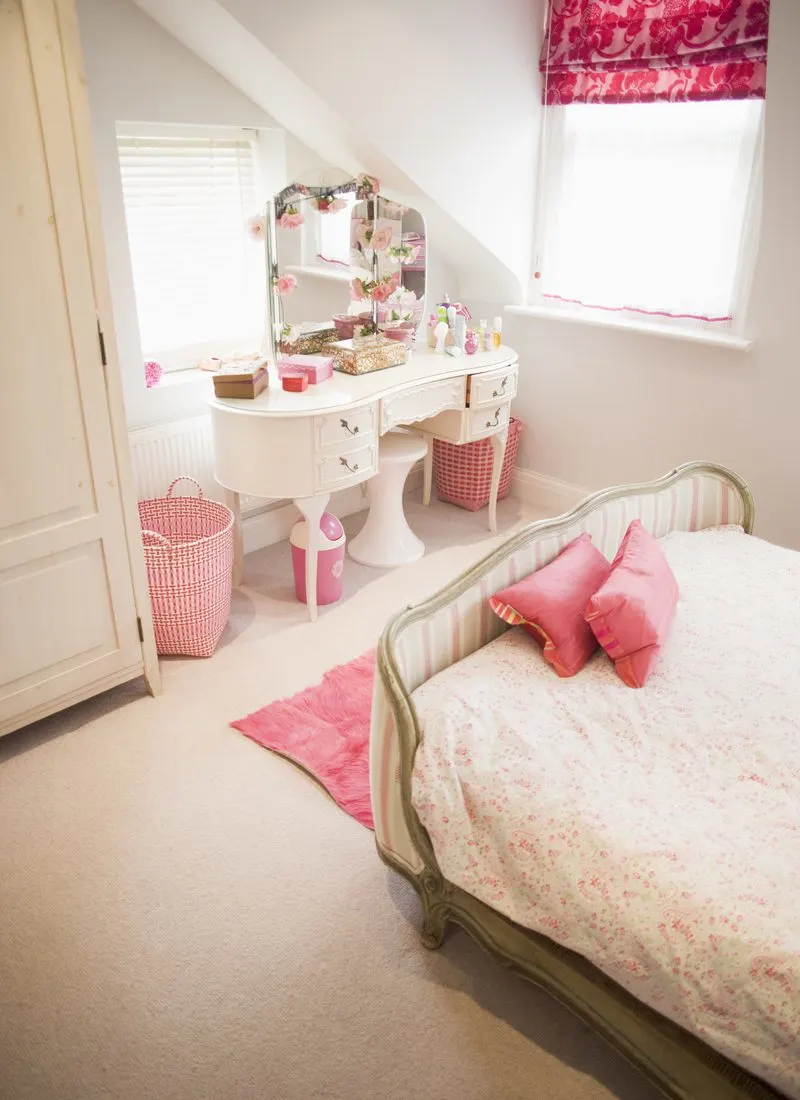 Image as part of a roundup of cute rooms for girls with a Victorian-style bed next to a vanity with a mirror at which to apply makeup and get ready