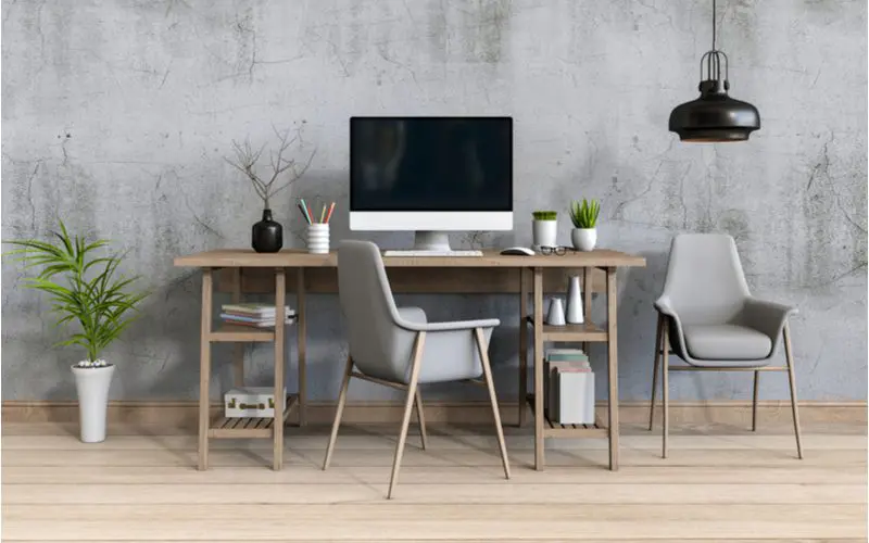 Sensible and Neat home office design idea with a grey wooden desk with open shelves on which sits a mac next to a grey sitting chair and potted plant