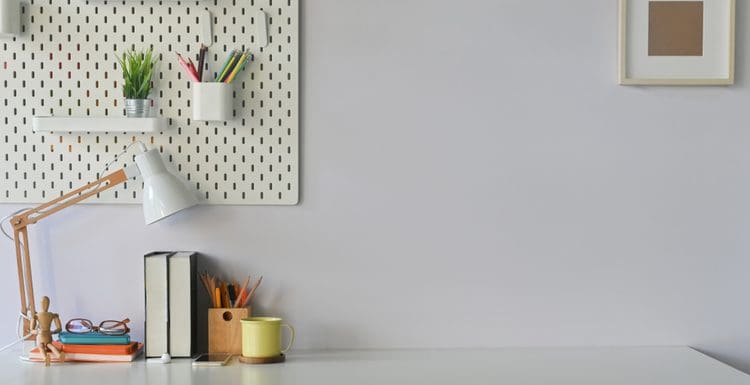 Featured image for a post titled office wall decor ideas featuring a simple close-up image of a pegboard with various attachments and a simple natural wood frame