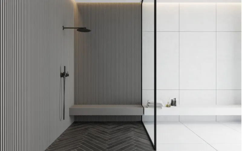 Floating shower bench in a blended grey and white shower divided by a glass wall