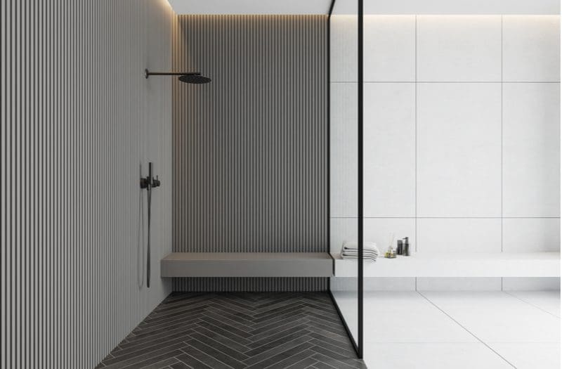 Average shower bench size as represented in an image of a tile and doorless shower with a glass divider and a herringbone tile floor
