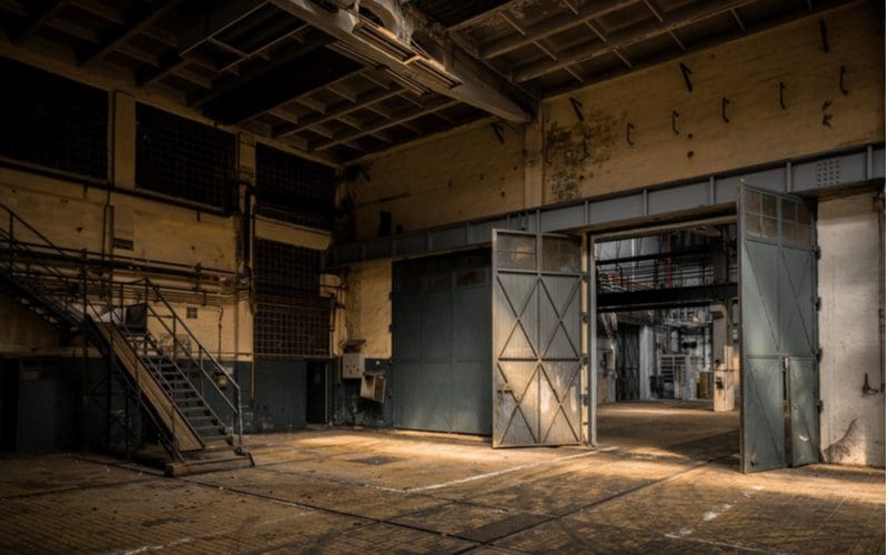 Old factory with big metal doors and a metal staircase in a dimly lit room for a piece on industrial styling ideas