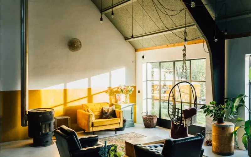 Eclectic, one of the different interior design styles, featuring an artist's studio-type aesthetic with hanging wicker chairs and a wood burning stove