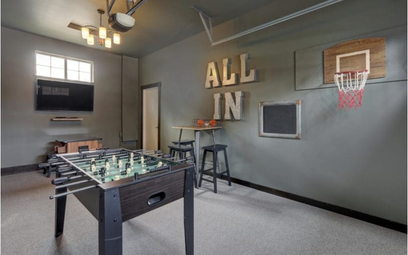 Bachelor pad idea showcasing a Garage Transformed into Sports Playroom featuring a basketball hoop mounted to the wall, a foosball table, and a pacman machine 