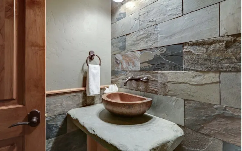 Stunning bathroom in the interior cabin style with slate stone on the walls and behind the counter