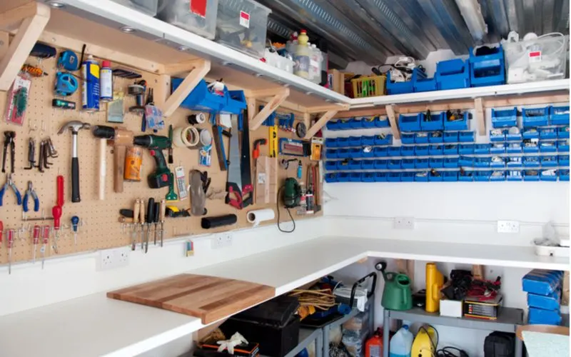 For a piece on bachelor pad ideas, a bunch of tools are hung on the walls of a workshop with ample small blue plastic bins for screws and bolts while the tools hang on a pegboard