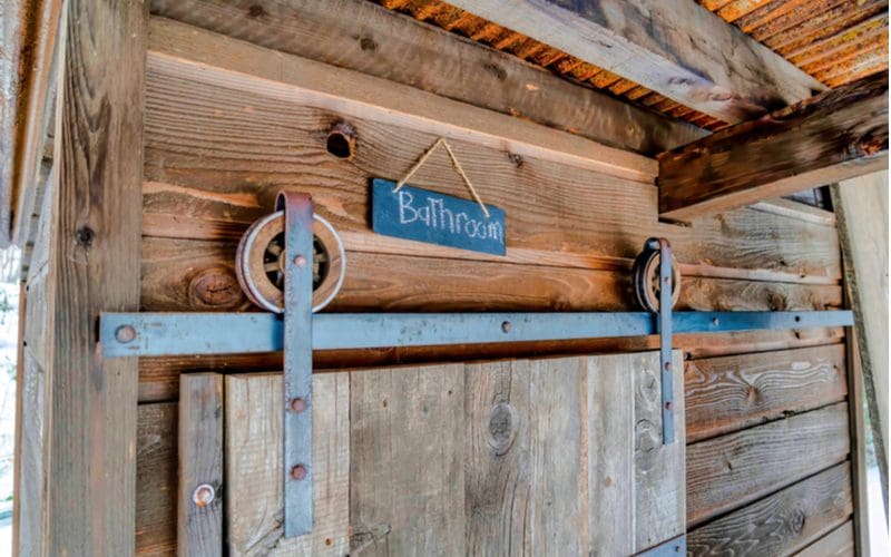Farmhouse-style sliding barn door in grey wood for a piece on modern rustic bathroom ideas