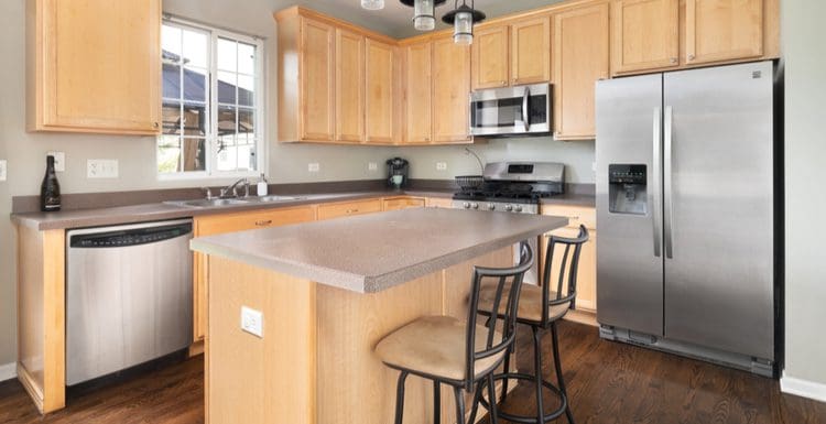 Image for a piece titled what color granite goes with honey maple cabinets featuring such cabinets in an open floorplan kitchen with stainless appliances