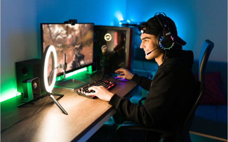 Gaming desk with a lighting rig in front of a streamer wearing a headset and smiling while playing Call of Duty for a piece on gaming setup ideas
