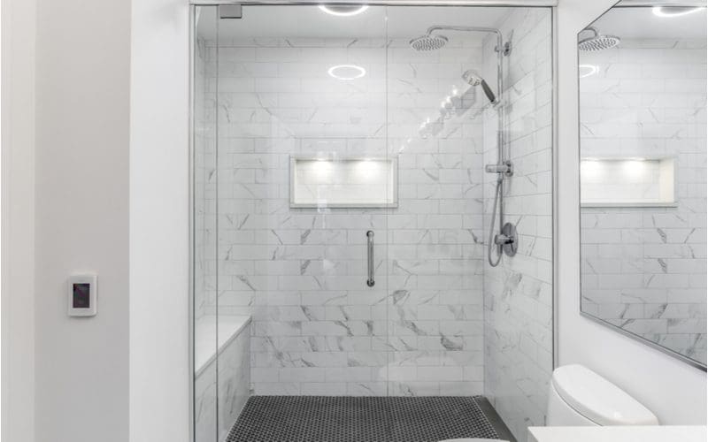 Shower with bench tiled with grey and white subway tile on the surround and dark grey tile on the ground
