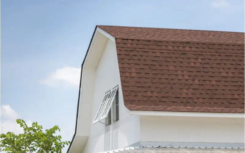 to answer the question what paint goes with a brown roof, a brown shingled roof sits on a white painted house with a gambrel roof