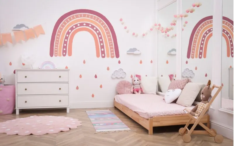 As an idea for cute rooms for girls, a herringbone floor made of wood with white walls on which rainbows are painted