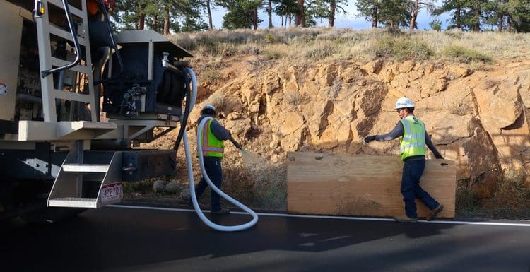 Man using a spray on grass seed machine to spray the side of a road in Estes Park