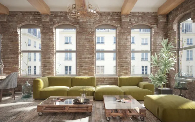 For a piece on industrial styling, a loft-style living room with big windows surrounding an open floorplan with a big green couch