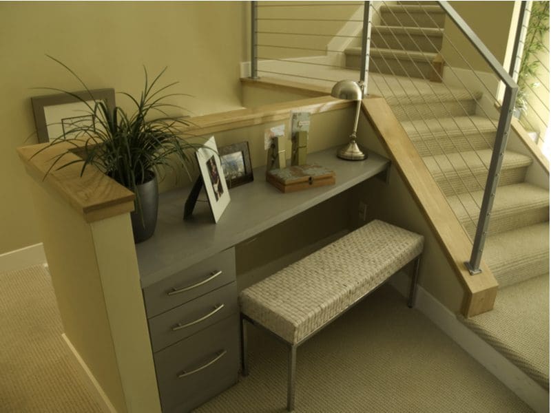 Home office design idea featuring a desk that's built into the staircase in sort of nook