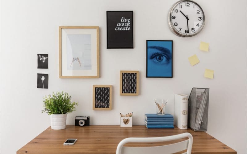 Image of a home office design idea with lots of pictures framed and mounted on the wall below a clock