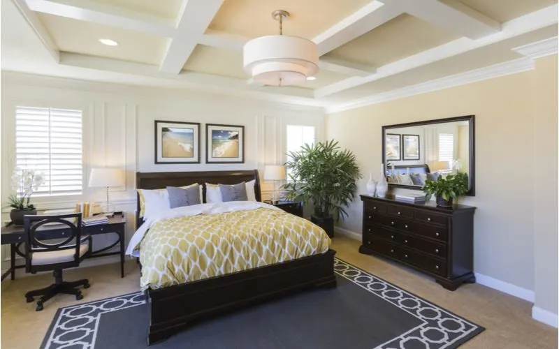 Idea for master bedroom decor featuring a dramatic interior of a taupe and beige room with white trim and a yellow and grey bed