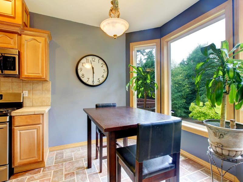 Simple Bay Window Breakfast Nook Expansion with a small two-person table, paver-style ceramic tile, and light oak cabinets