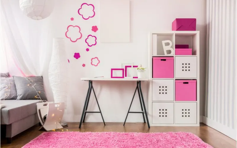 Cute room for girls idea with pink and white storage cubes next to a small easel-style desk below a pink cloud wall decoration and paper lamp