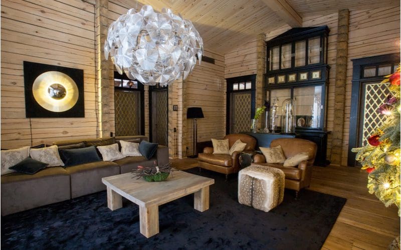 Grand and lavish cottage interior idea with pine paneling on the walls and ceiling with dark blue plush rugs and round record lights on the walls