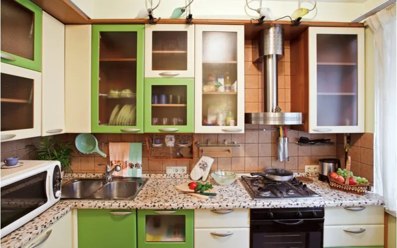 Rustic cabinets painted green and cream in a funky modern kitchen with a rustic flair