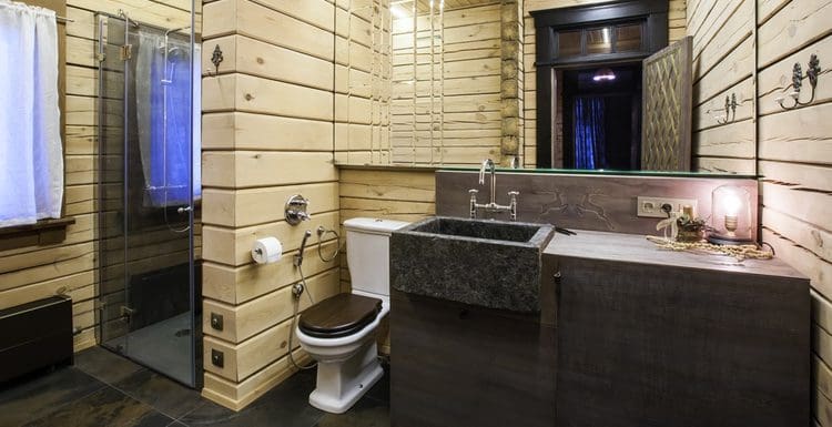 Modern rustic bathroom idea featured image with natural pine wall covering and dark slate floor tile and a stone faucet